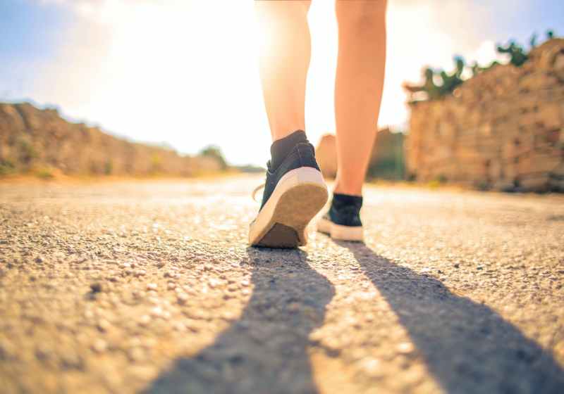 woman walking on pathway under the sun
